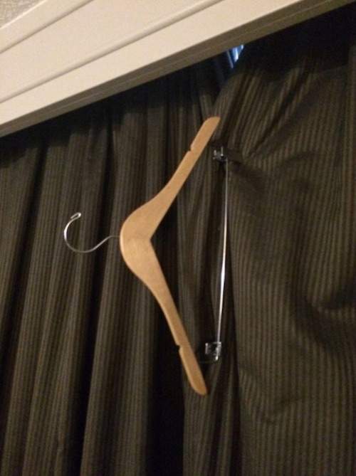 un cintre est accroché à 2 rideaux pour empêcher les lumières extérieures d'éclairer la chambre