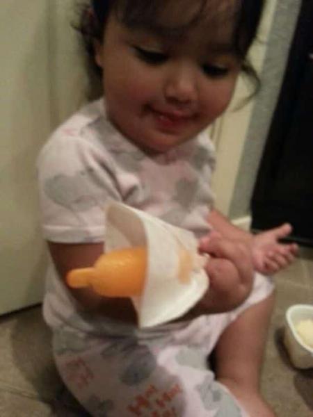 une petite fille mange un bâtonnet tenu dans un filtre à café