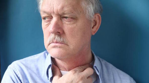 un homme âgé se tient la gorge