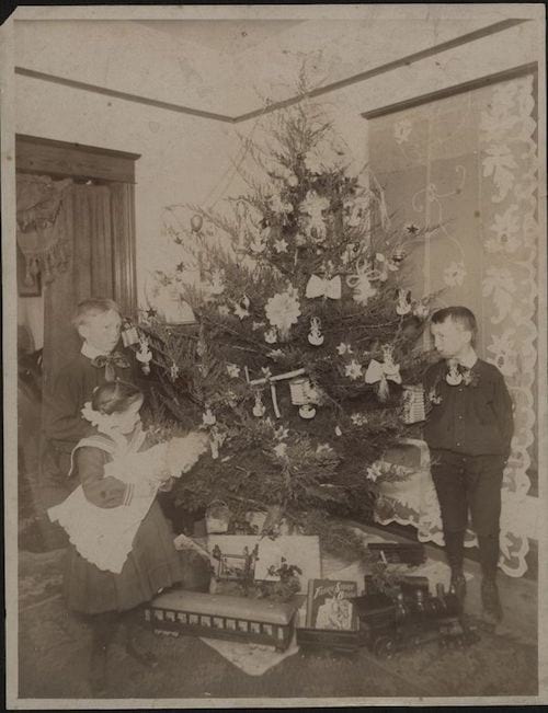 des enfants posent devant un sapin et leurs cadeaux