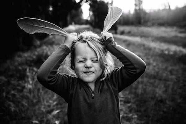 photo en noir et blanc de Nikki Boon de sa fille qui joue  avec des feuilles