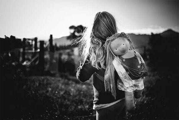 photo en noir et blanc d'une petite fille qui joue avec sa poupée