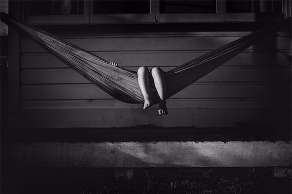 un enfant est allongé dans un hamac et seuls ses pieds ressortent sur cette photo en noir et blanc