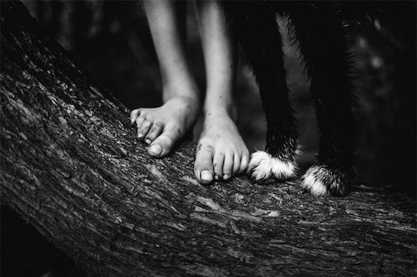 Photo en noir et blanc des pieds d'un des enfants de Nikki Boon avec un chien