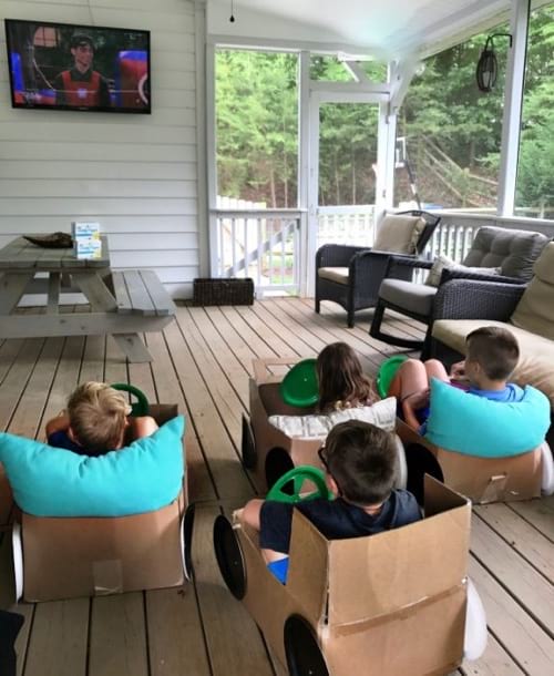 des enfants regardent un film à la télé installé dans des voitures en carton