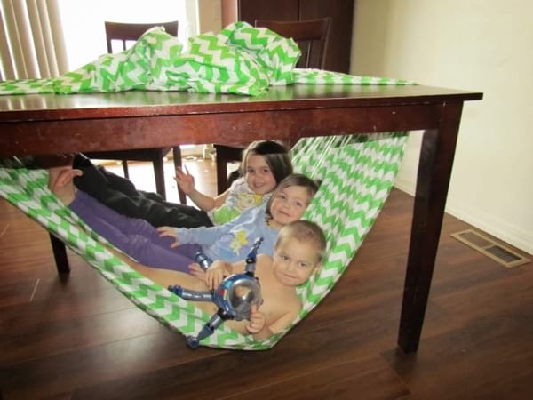 un hamac pour les enfants fait avec un drap accroché sous une table
