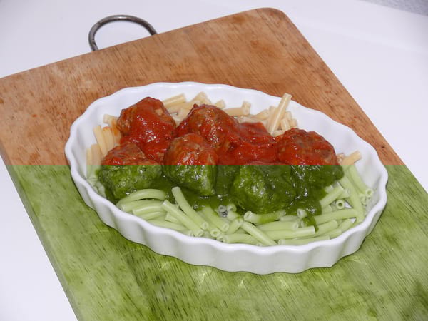 Plat blanc avec des pates et des boulettes à la sauce tomate