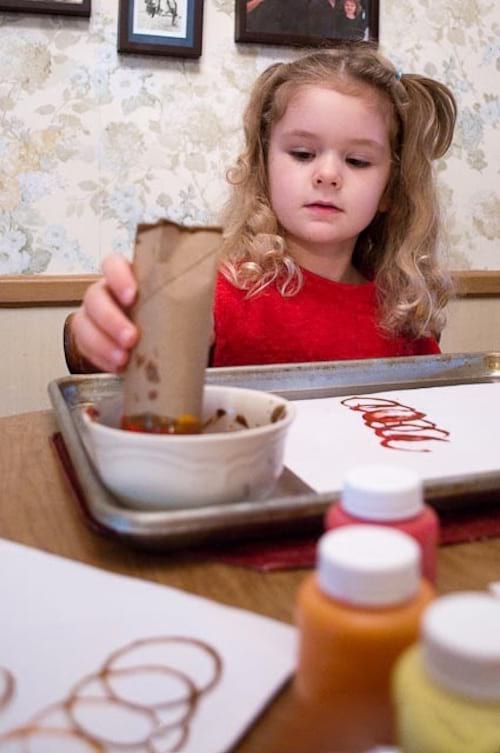 une petite fille fait des dessins avec des tampons faits maison