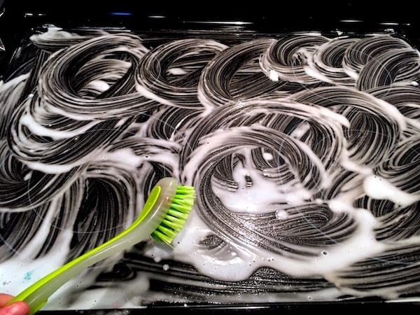 la plaque de cuisson est frottée avec une brosse en faisant des ronds pour mélanger les produits