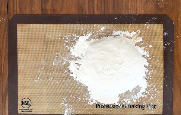 a ball of bread dough placed on a surface full of flour