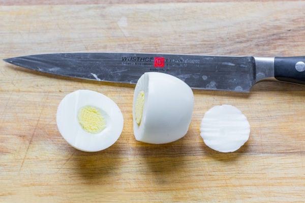 un oeuf dur est coupé avec un couteau aiguisé d'1/3 au sommet et une fine tranche en bas