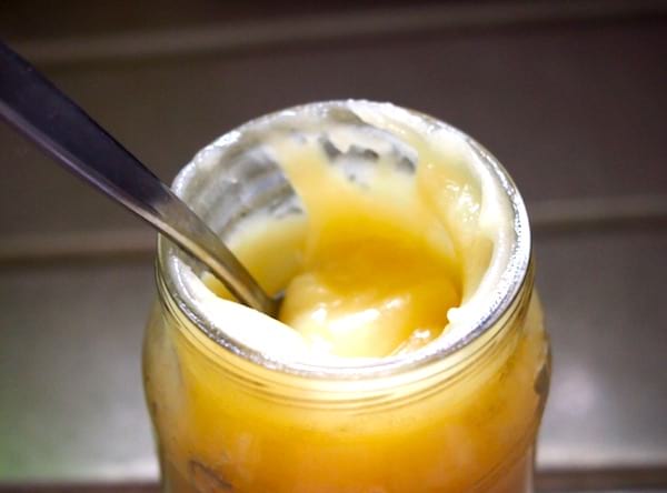 Un petit pot en verre avec de la crème hydratante faite maison.