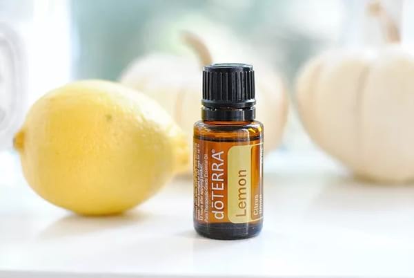 une bouteille d'huile essentielle de citron et un citron, deux produits qui luttent contre la cellulite