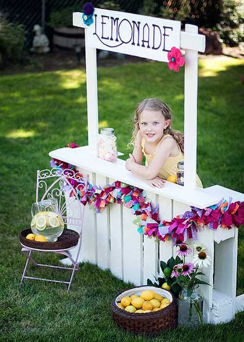 un stand à boissons blanc en palette pour avec une petite fillequi  joue à la marchande