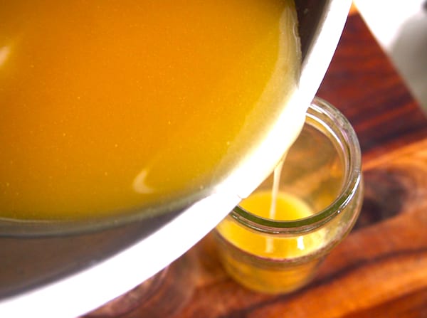 Du miel, de l'huile d'amande douce et da la cire d'abeille fondus versés dans un bocal en verre pour une crème hydratante maison.