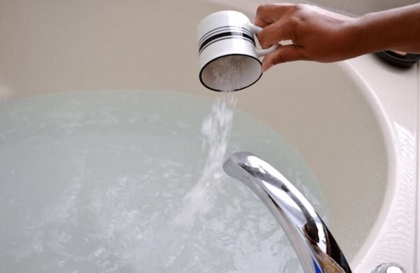 du sel d'Epsom versé dans un bain chaud pour se relaxer