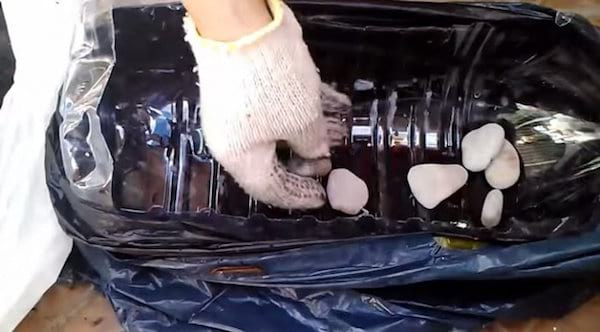 des pierres sont placées au fond de la bouteille en plastique coupée en deux avant de mettre les graines de tomates