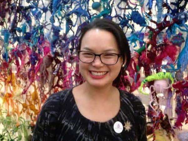 femme qui sourit devant un mur de neurones tricotées à la main