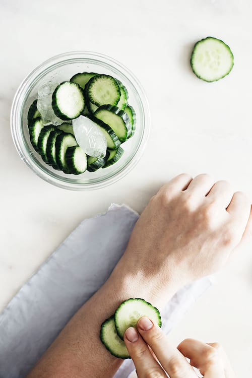 Une femme qui utilise des concombres pour soigner un piqûre de moustique.