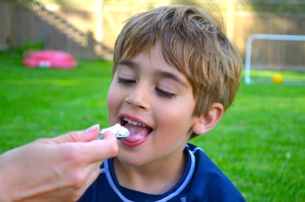 Un enfant qui mange de la crème glacée maison préparée dans un sac congélation.