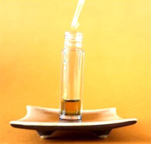 Un compte-gouttes qui versent des huiles essentielles dans un flacon, pour faire un sérum anti-rides.