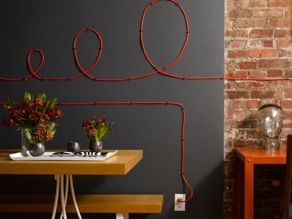 des fils électriques rouges installés sur un mur noir
