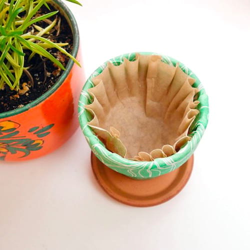 Astuce jardinage : utilisez un filtre à café pour empêcher l’eau de couler trop rapidement de vos pots de fleurs.