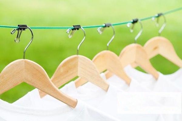 Plusieurs cintres accroch&eacute;s sur un fil vert gr&acirc;ce aux &eacute;pingles