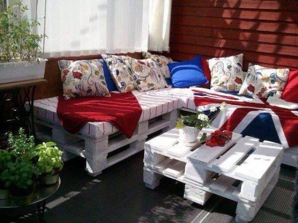 Canapé superposé sur plusieurs palettes en bois blanc avec des coussins 