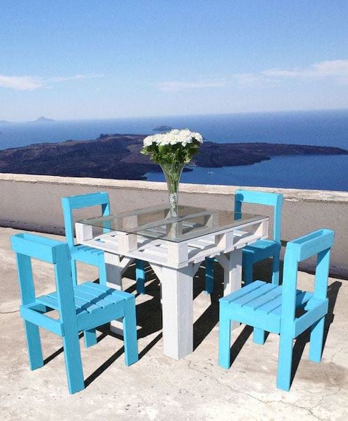 Plusieurs chaises bleu et une table blanche fait avec des palettes en bois 