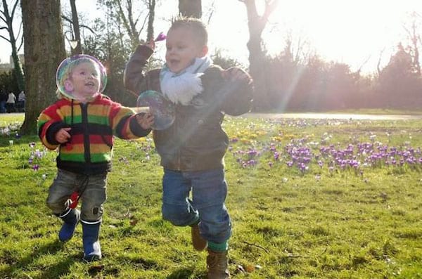 Deux enfants qui jouent avec des bulles dans une forêt