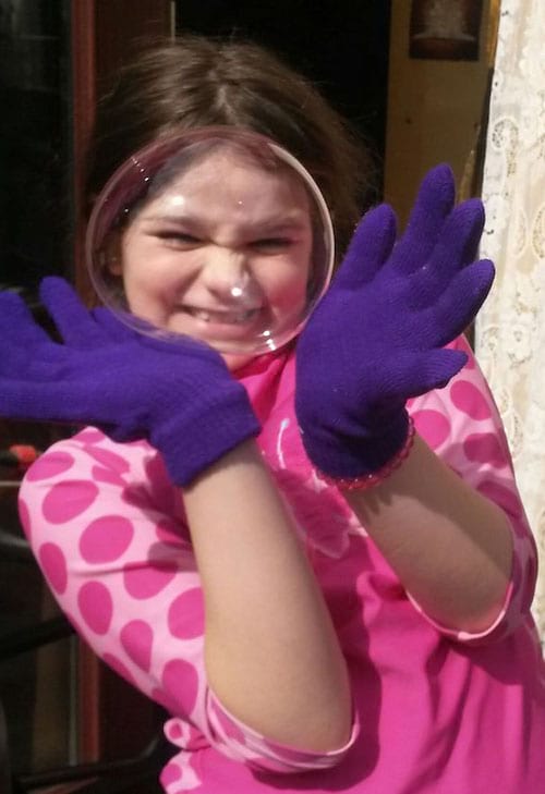 Fille équipée de gants violet entourant une bulle avec ses mains