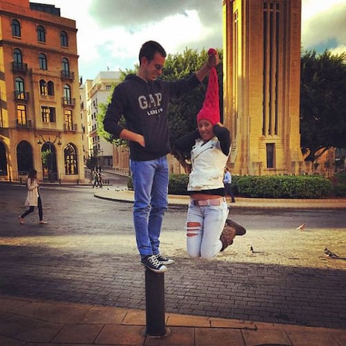 Homme sur mini poteau tenant le bonnet rouge d'une femme