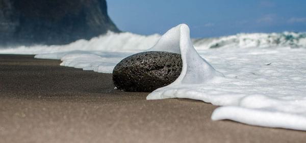 Mini rocher sur la plage qui soulève l'eau de la mer