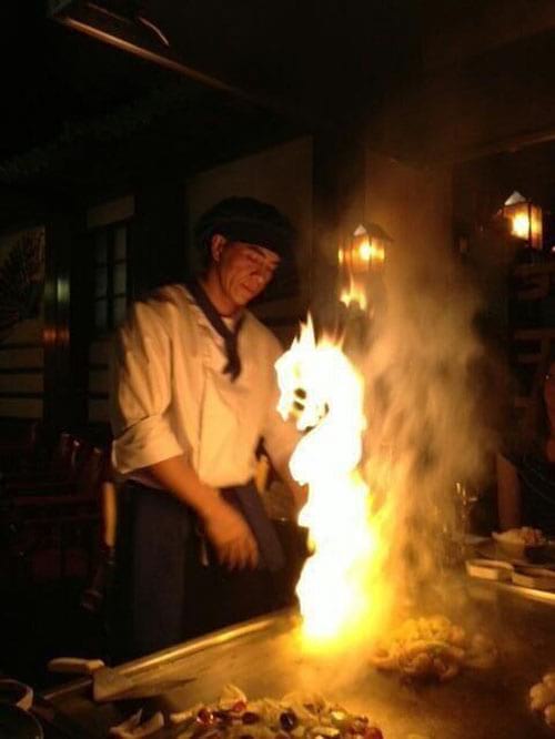 Une personne cuisine avec devant elle des flammes en forme de dragon