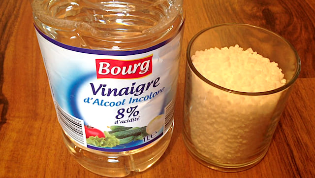 Une bouteille de vinaigre blanc et un verre de gros sel pour détarter la machine à laver