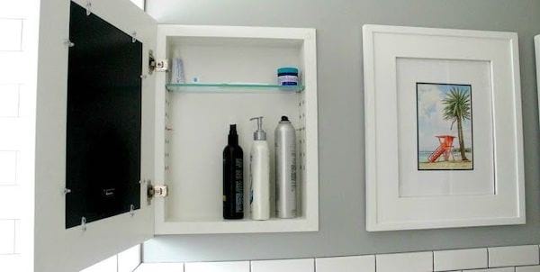 Petite armoire de rangement derrière un cadre dans le mur 