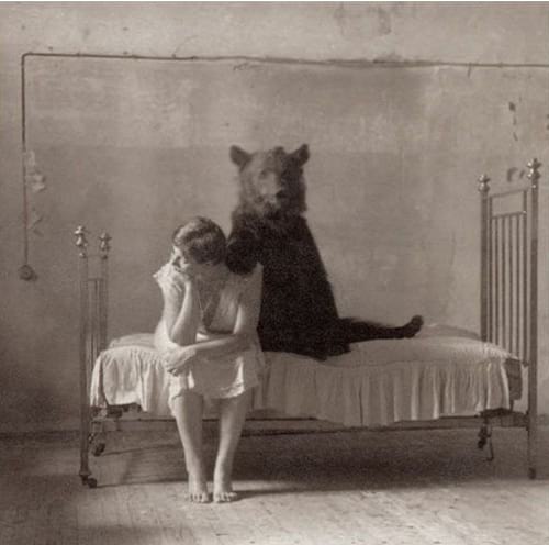 Femme assise sur un lit et un ours à côté d'elle