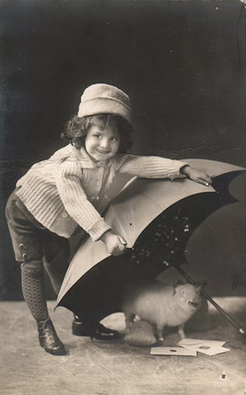 Petite fille tenant un parapluie à terre avec un petit cochon en dessous du parapluie