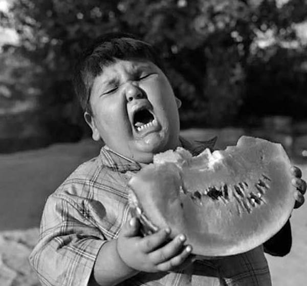 Garçon qui mange une pastèque avec tête souffrante