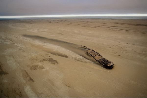 Désert au Namibie avec un bateau abandonné dans le sable 