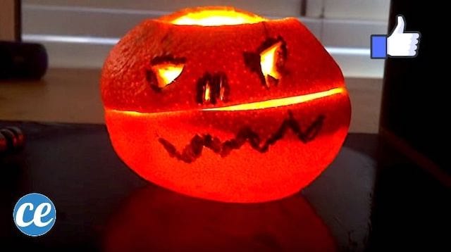 Une bougie Halloween allumée faite avec une orange posée sur la table