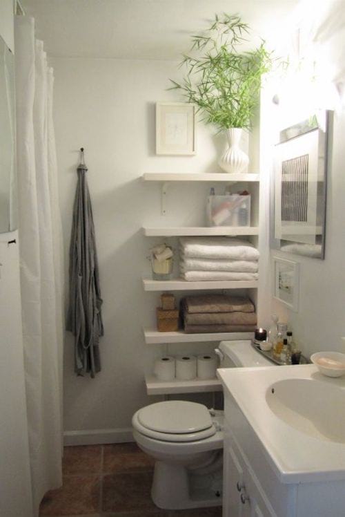 Plusieurs étagères blanche dans une salle de bain qui servent rangements pour tout 