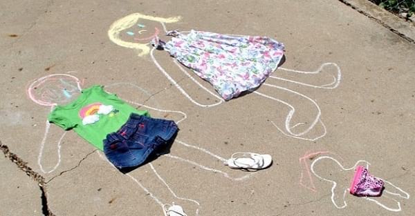 Des silhouettes de poupées dessinées à la craie sur le sol et habillées avec de vieux vêtements