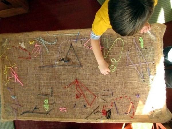 Un enfant fait de la couture sur une grande toile de jute