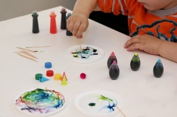 Un enfant fait de la peinture avec de la colle et des colorants alimentaires