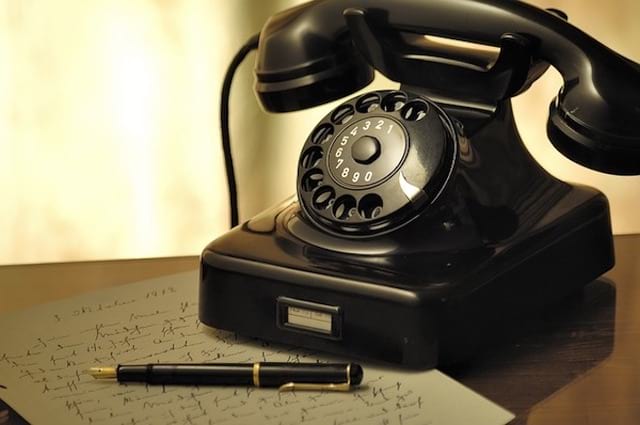 Un vieux téléphone posé sur une table avec un crayon et une lettre
