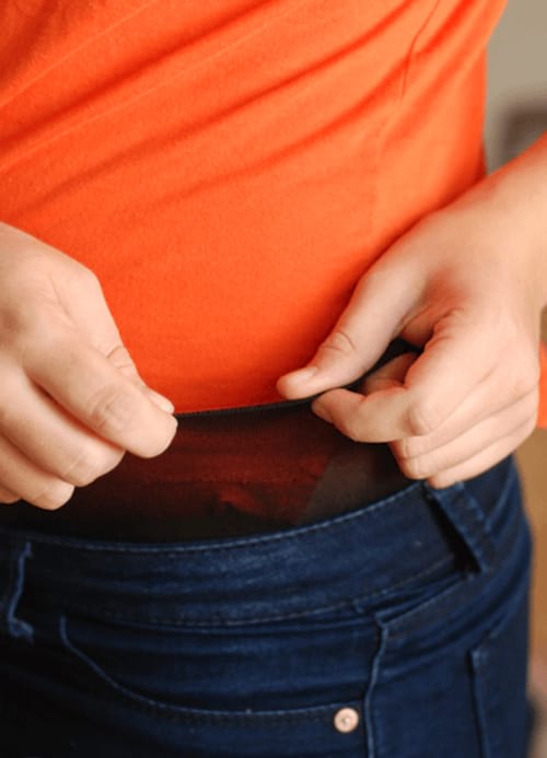 Un collant filé sous un jeans bleu avec un t-shirt orange