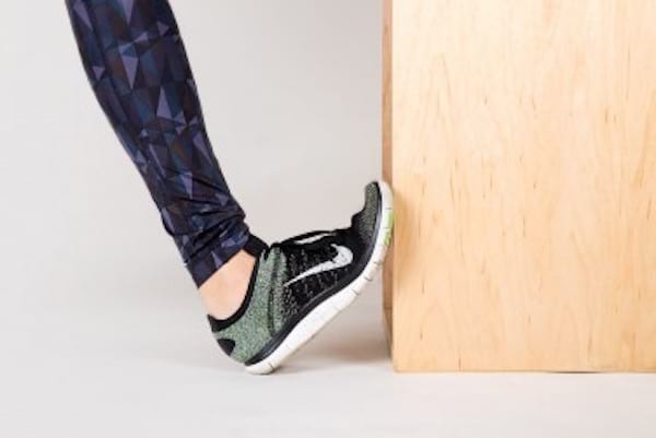 Étirements d'un pied contre le mur contre les douleurs aux genoux