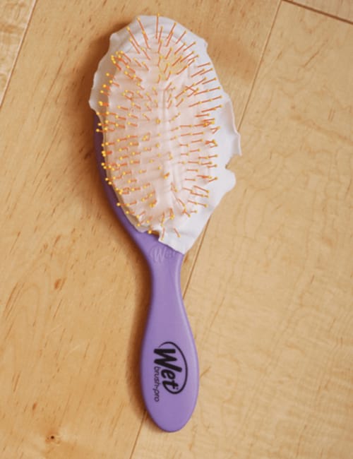 Une brosse à cheveux avec un morceau de nylon dessus pour faciliter le nettoyage